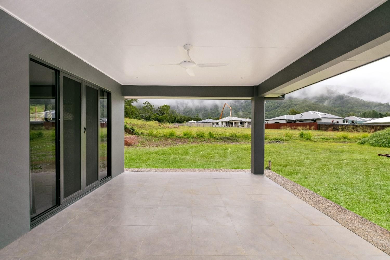 An Empty Patio With a View of a Grassy Field and Mountains — Ashlee Jones Homes in Gordonvale, QLD