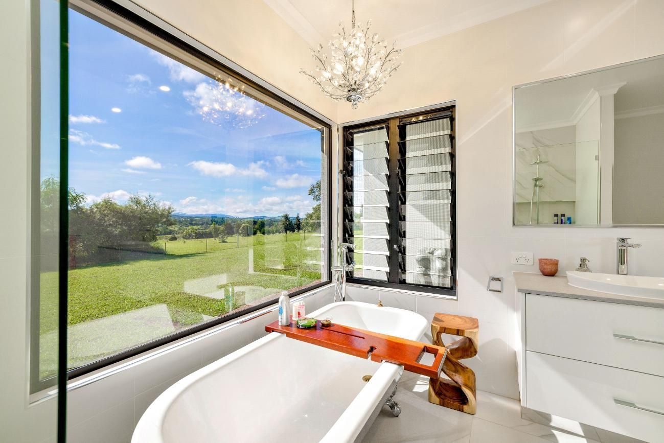 A Bathroom With a Bathtub, Sink, Mirror and Large Window — Ashlee Jones Homes in Gordonvale, QLD