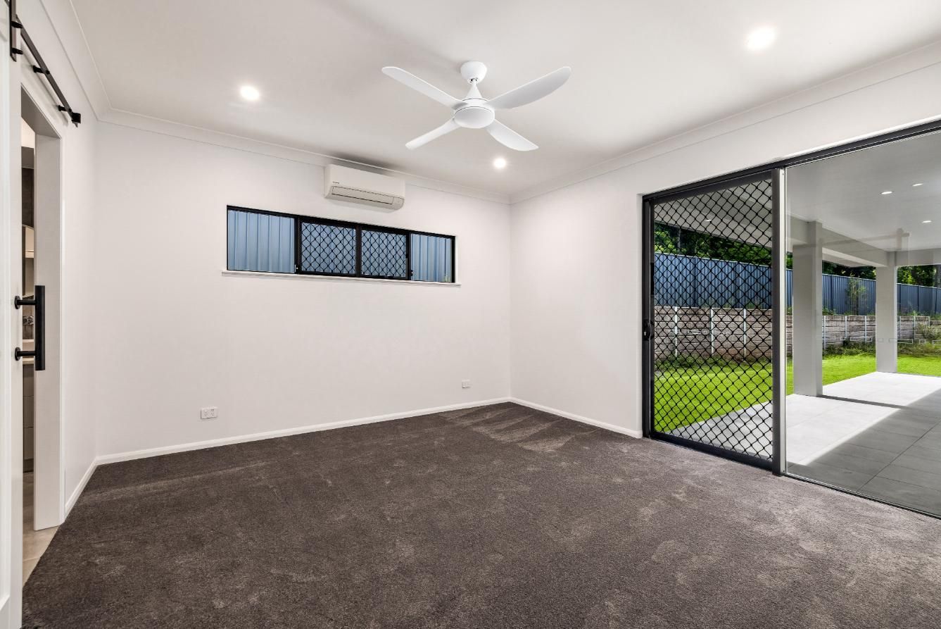 An Empty Living Room With a Ceiling Fan and Sliding Glass Doors — Ashlee Jones Homes in Gordonvale, QLD
