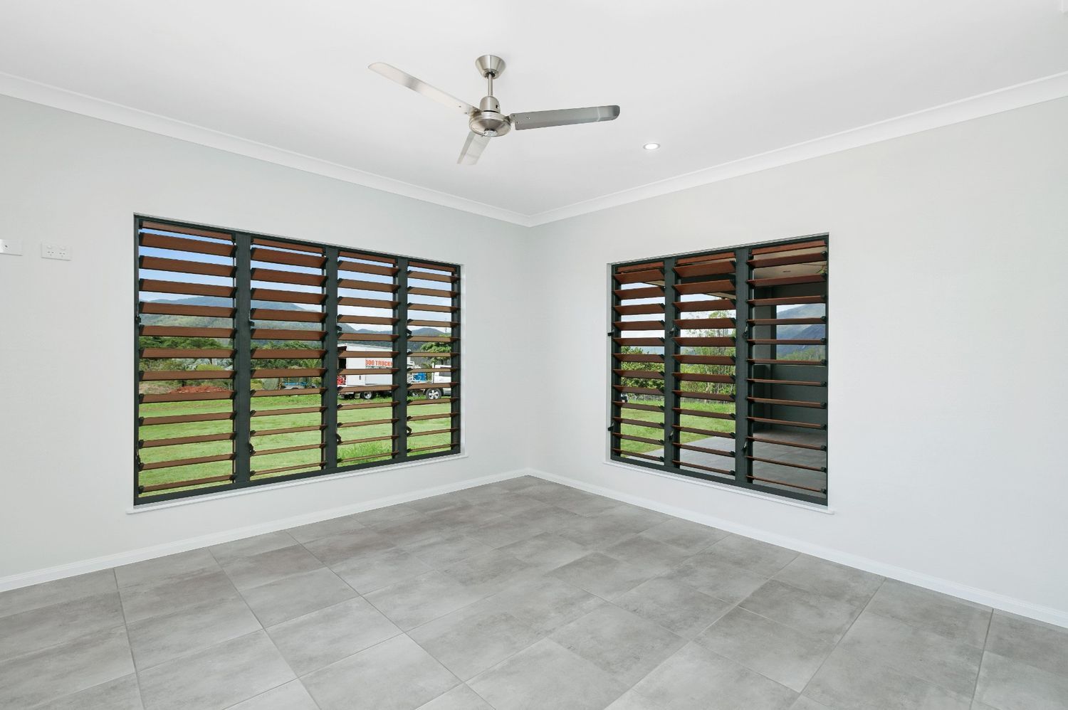 An Empty Room With Two Windows and a Ceiling Fan — Ashlee Jones Homes in Gordonvale, QLD