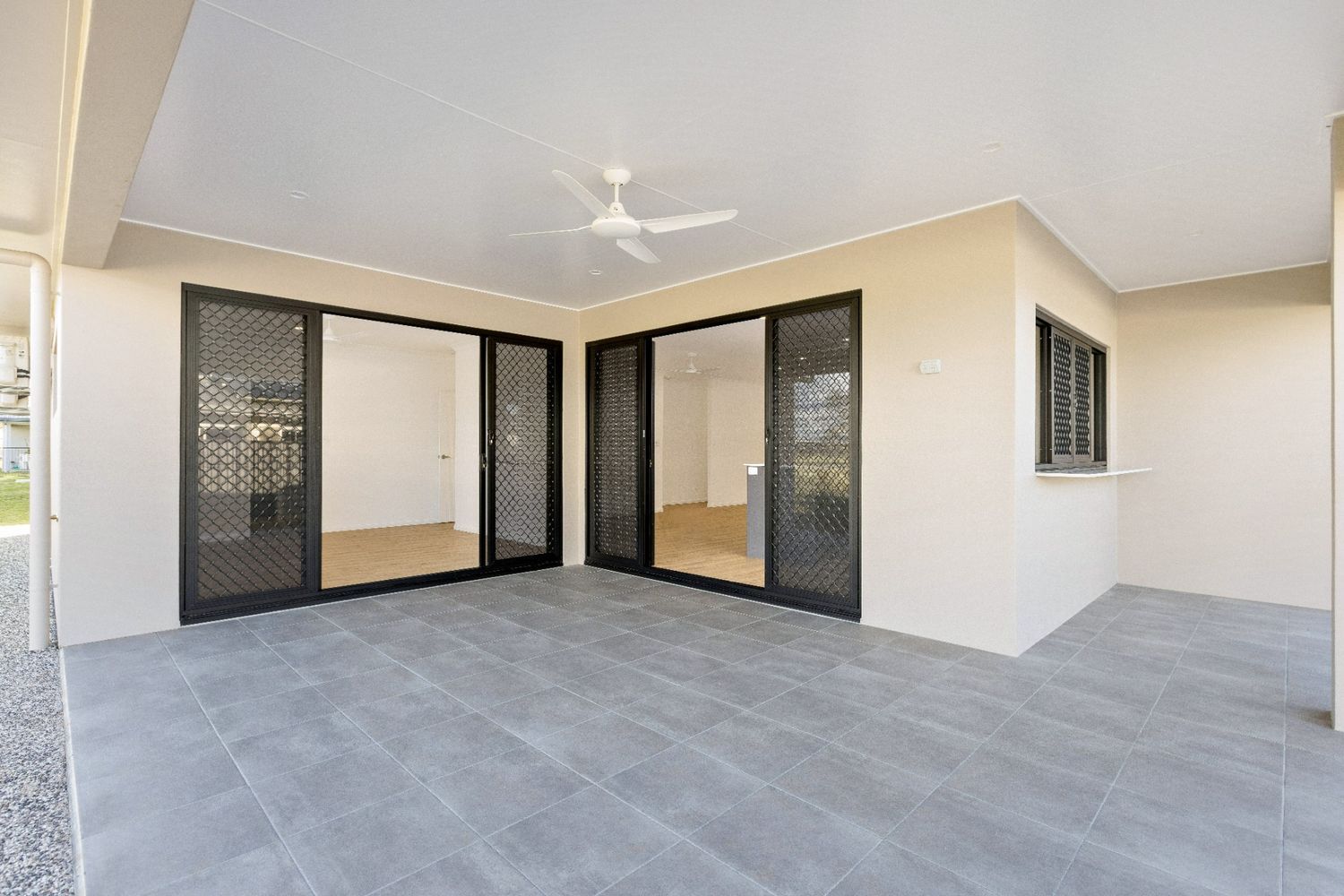 A Large Patio With Sliding Glass Doors and a Ceiling Fan — Ashlee Jones Homes in Gordonvale, QLD