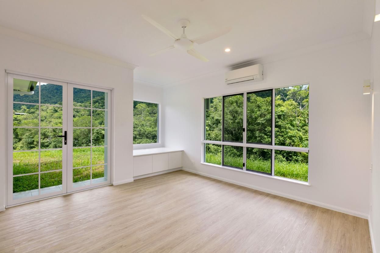 An Empty Living Room With a Lot of Windows and a Ceiling Fan — Ashlee Jones Homes in Gordonvale, QLD