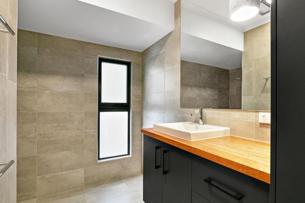 A Bathroom With a Sink, Mirror and Window — Ashlee Jones Homes in Gordonvale, QLD