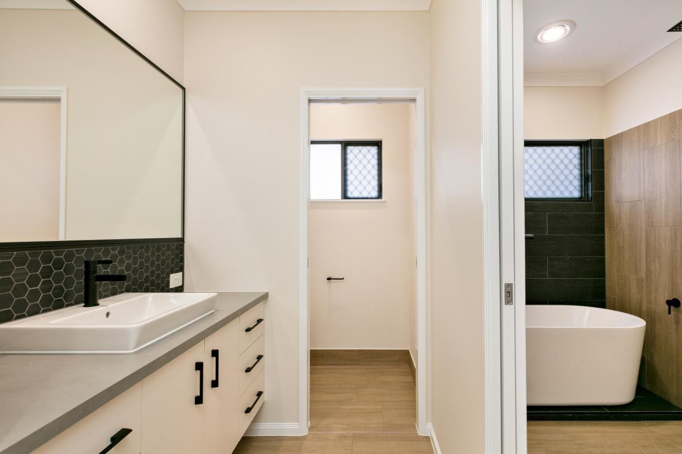 A Bathroom With a Sink, Mirror and Tub — Ashlee Jones Homes in Gordonvale, QLD
