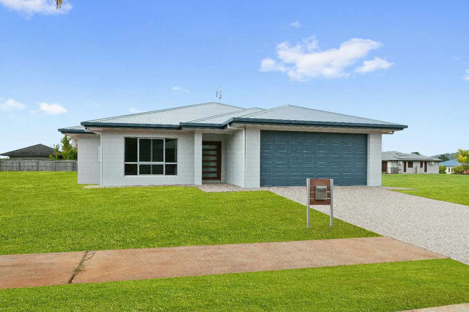A Couple of Houses Are Sitting on Top of a Lush Green Hillside — Ashlee Jones Homes in Gordonvale, QLD