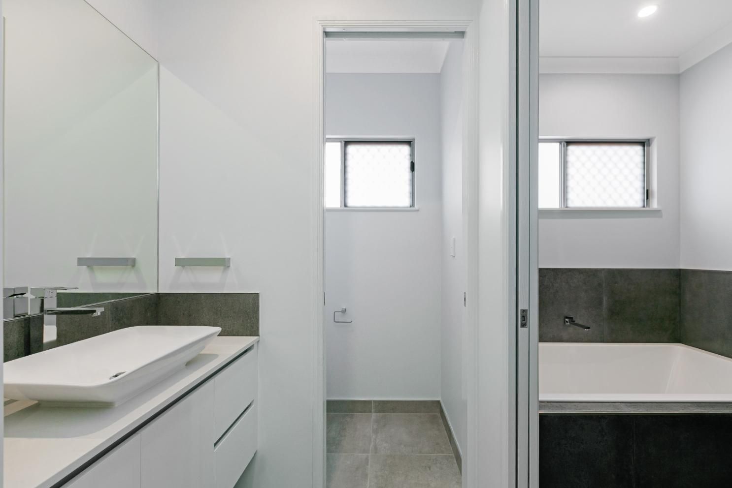 A Bathroom With a Sink, Mirror, Tub and Window — Ashlee Jones Homes in Gordonvale, QLD