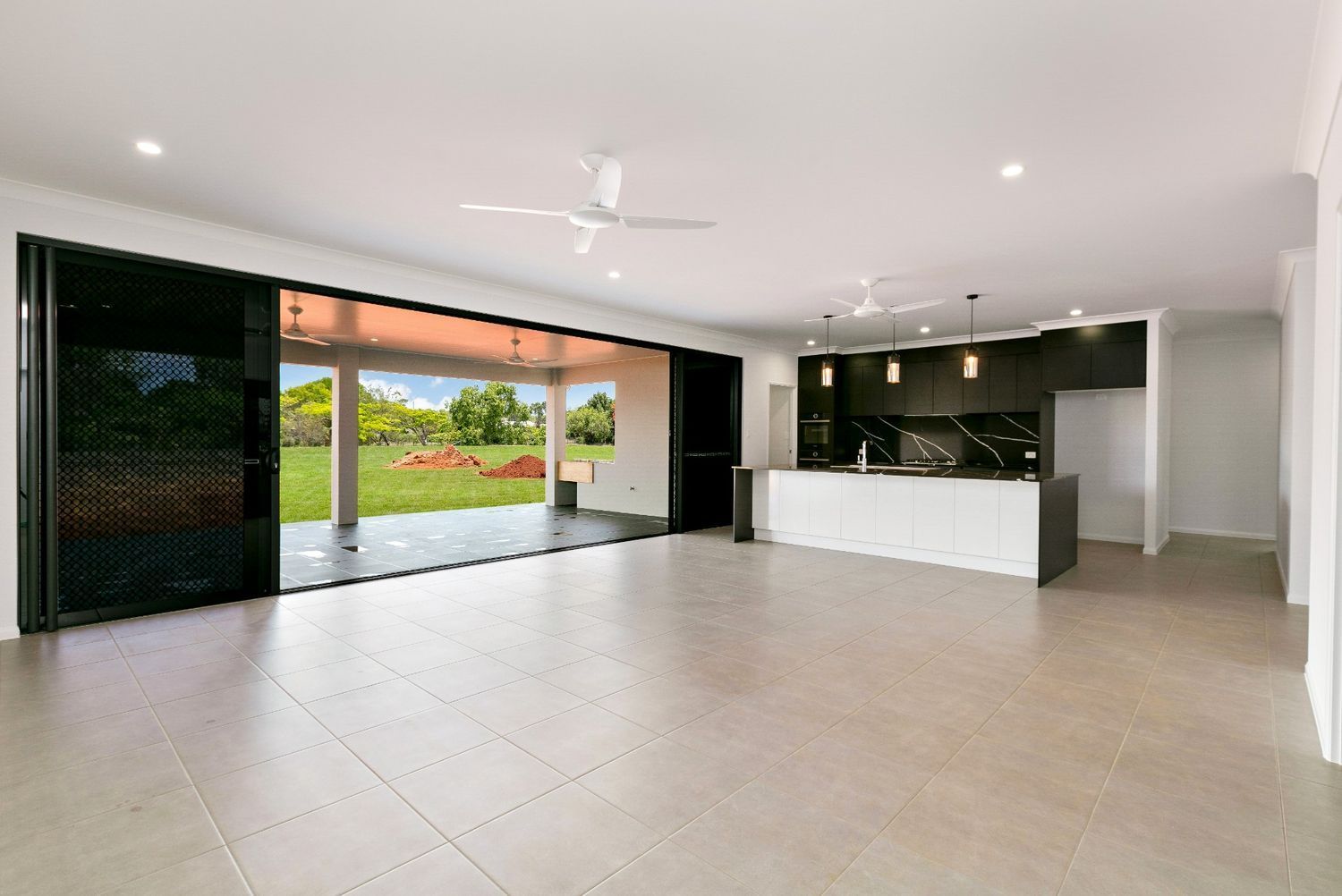 A Large Empty Room With a Kitchen and a Ceiling Fan — Ashlee Jones Homes in Gordonvale, QLD