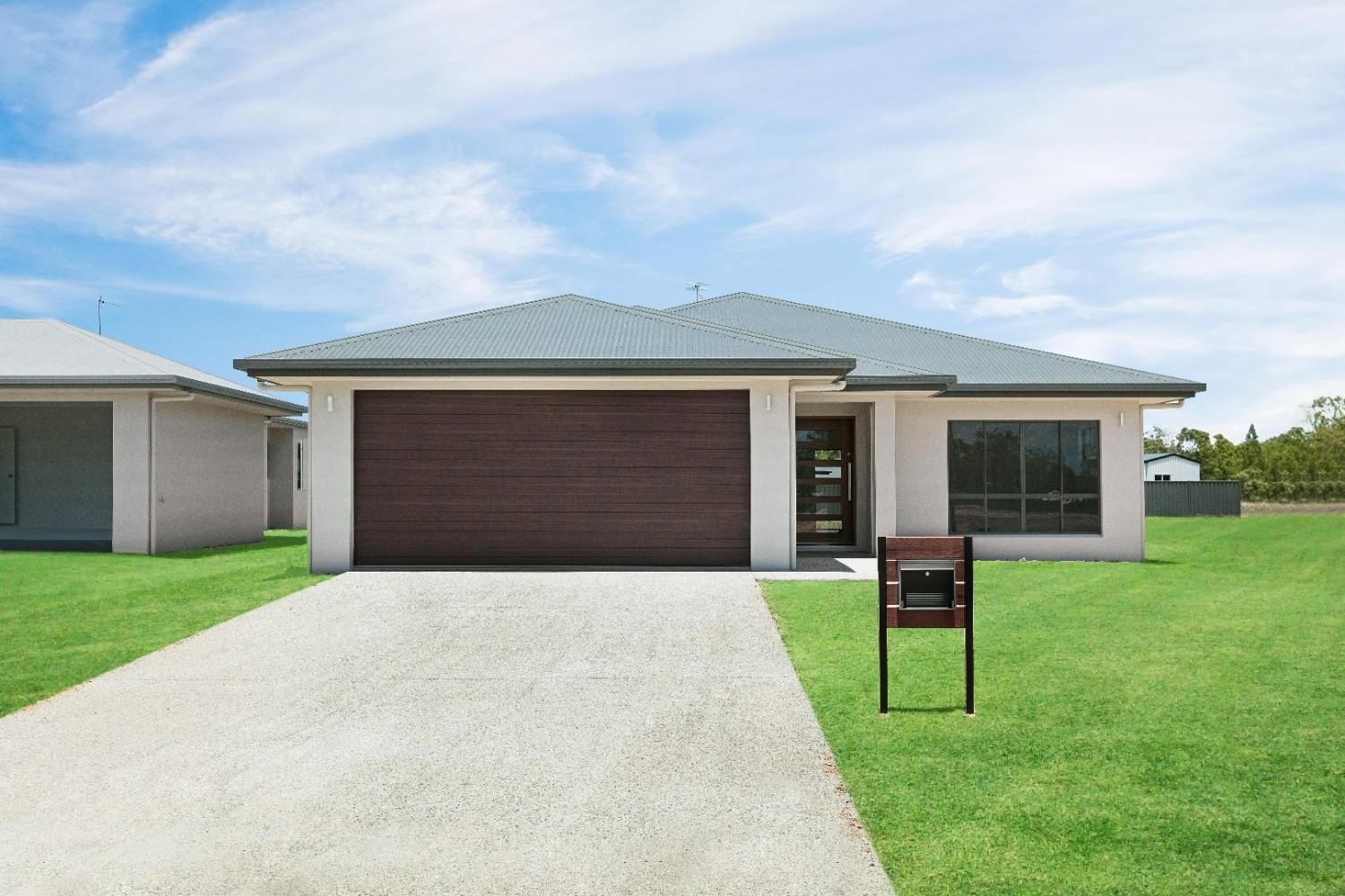 A White House With a Brown Garage Door and a Mailbox in Front of It — Ashlee Jones Homes in Gordonvale, QLD