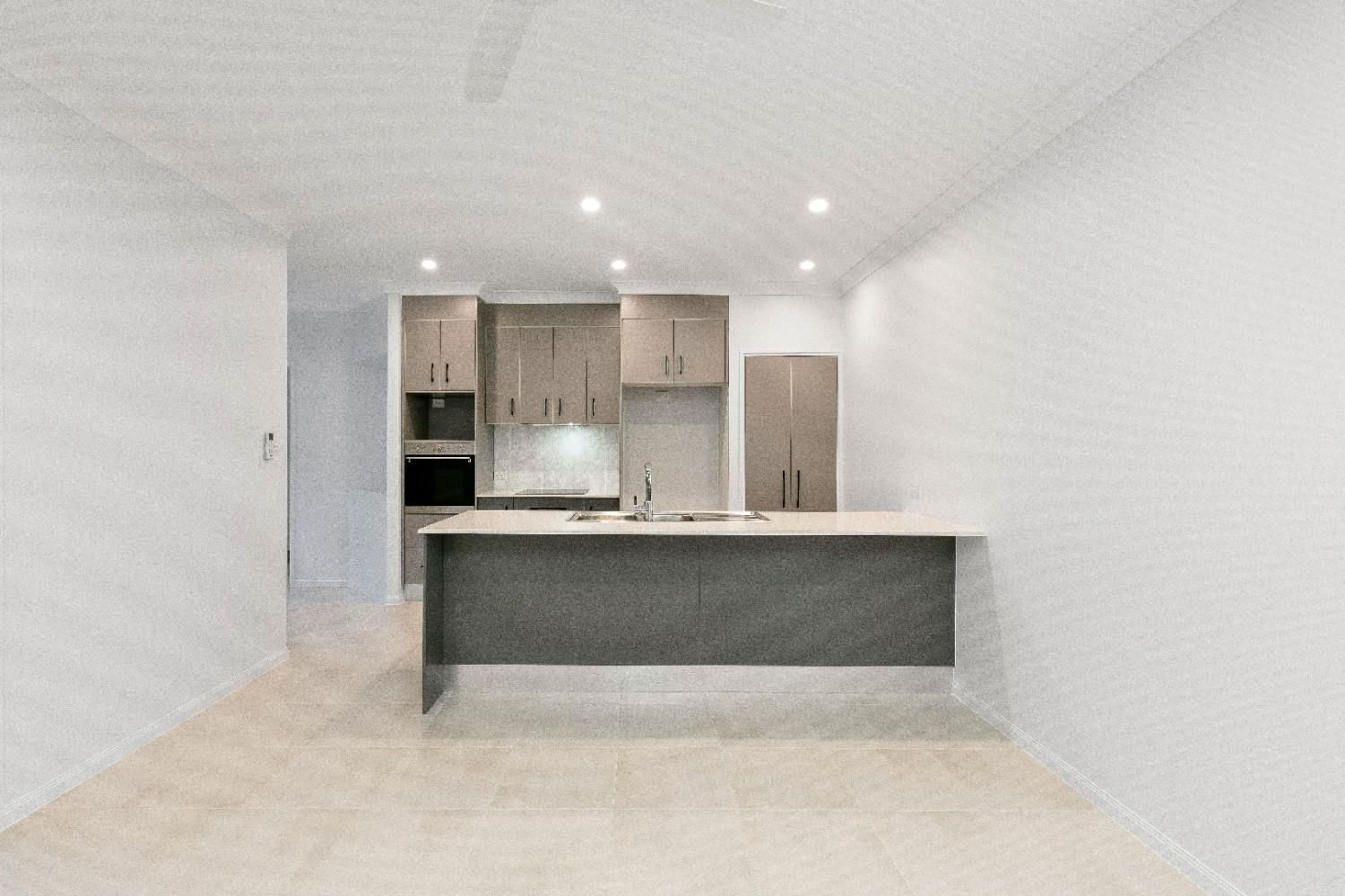 An Empty Kitchen With a Large Island in the Middle of the Room — Ashlee Jones Homes in Gordonvale, QLD
