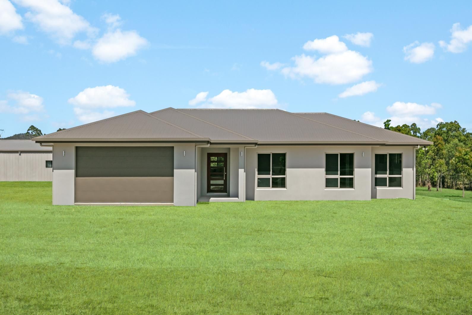 A House is Sitting on Top of a Lush Green Field — Ashlee Jones Homes in Gordonvale, QLD