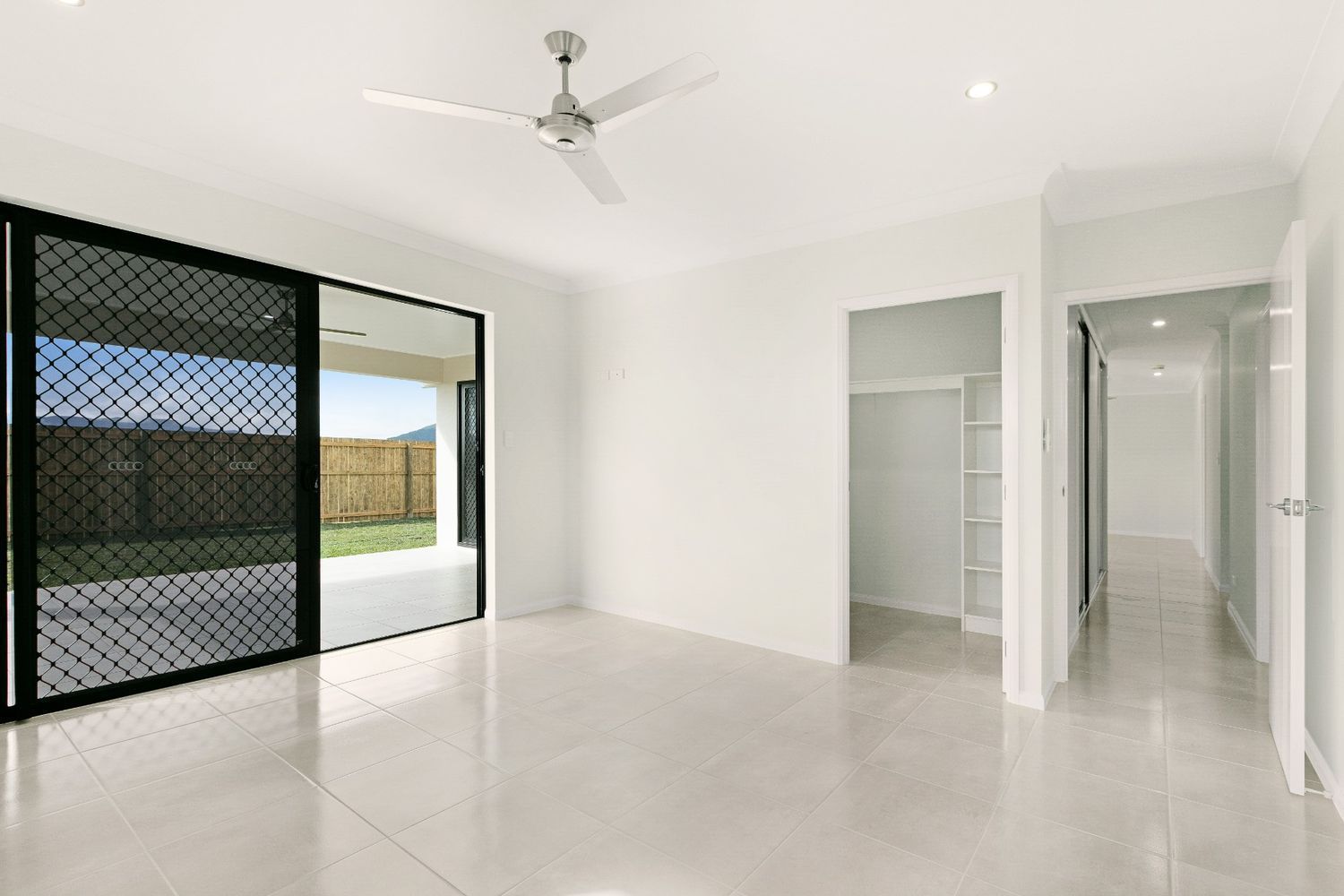 An Empty Room With a Ceiling Fan and Sliding Glass Doors — Ashlee Jones Homes in Gordonvale, QLD