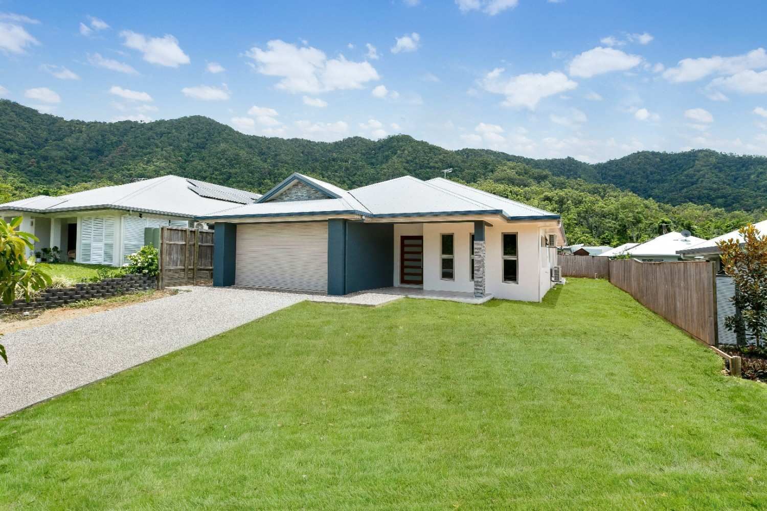 A House With a Lot of Grass in Front of It and Mountains in the Background — Ashlee Jones Homes in Gordonvale, QLD