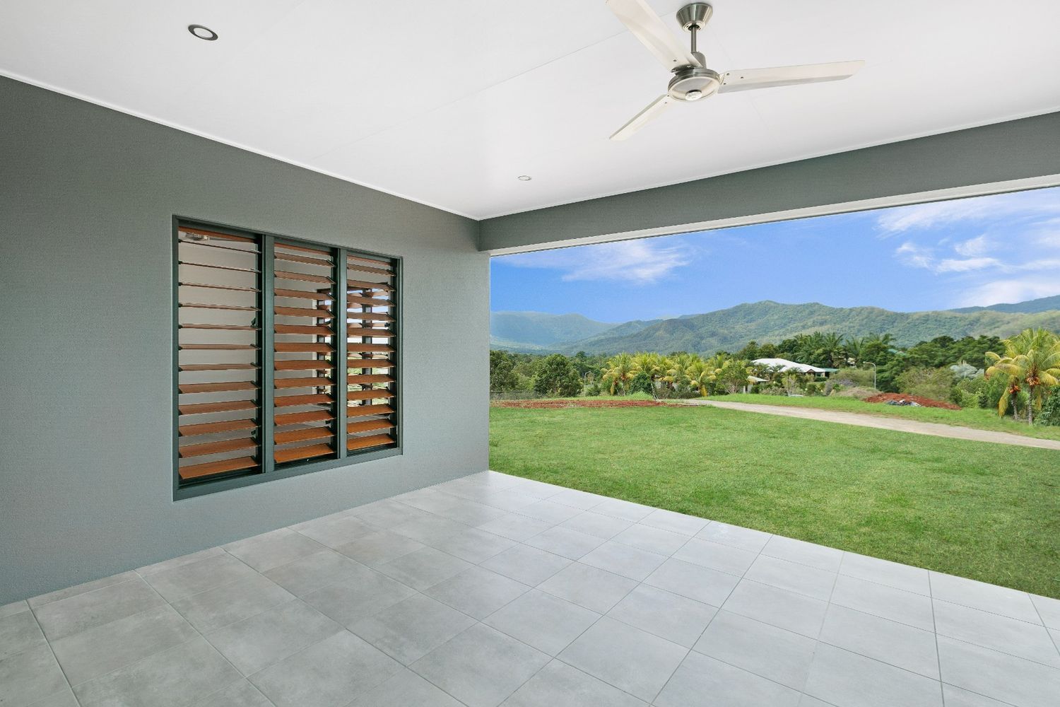 An Empty Patio With a Ceiling Fan and a View of a Lush Green Field — Ashlee Jones Homes in Gordonvale, QLD