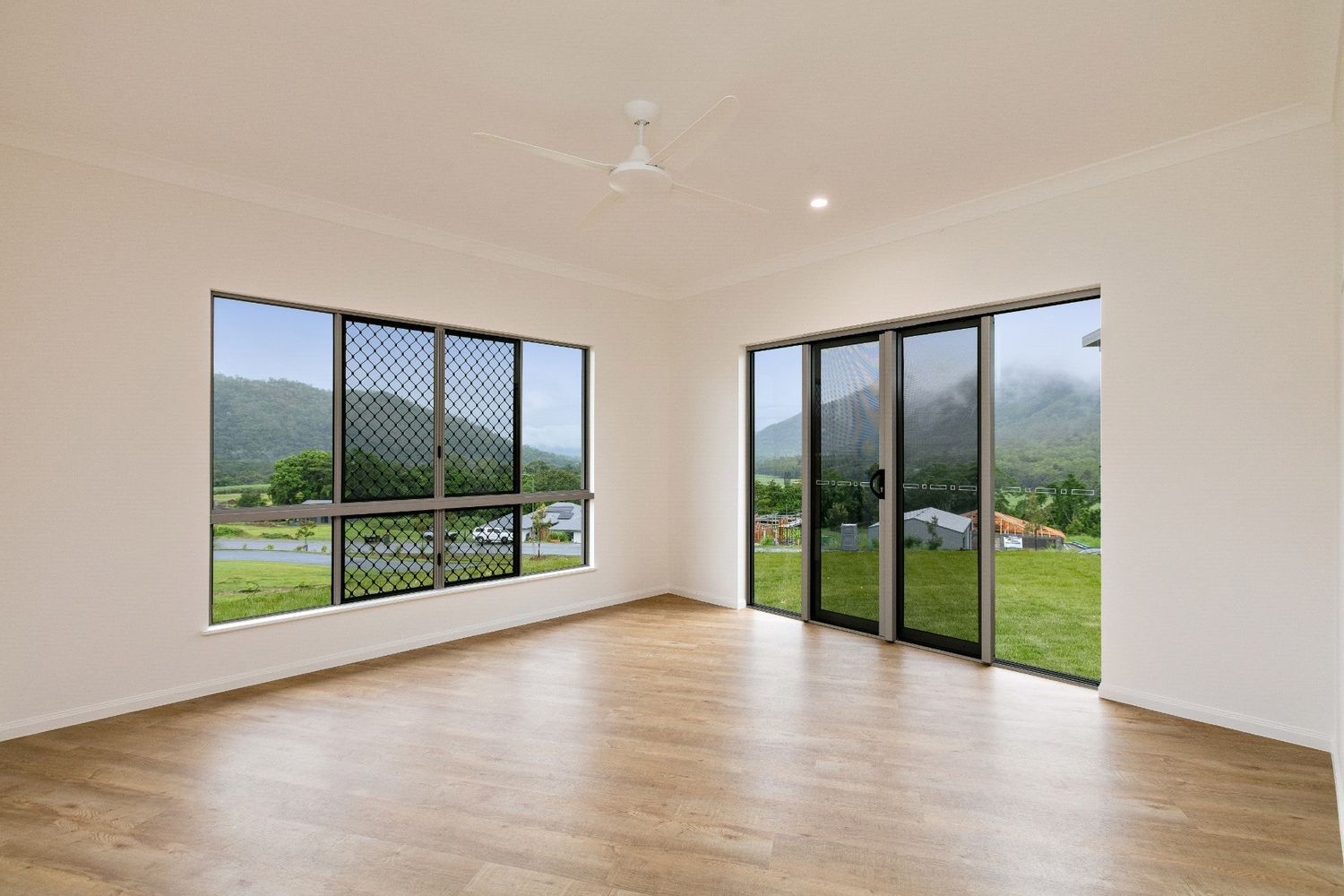 An Empty Living Room With a Lot of Windows and a Ceiling Fan — Ashlee Jones Homes in Gordonvale, QLD