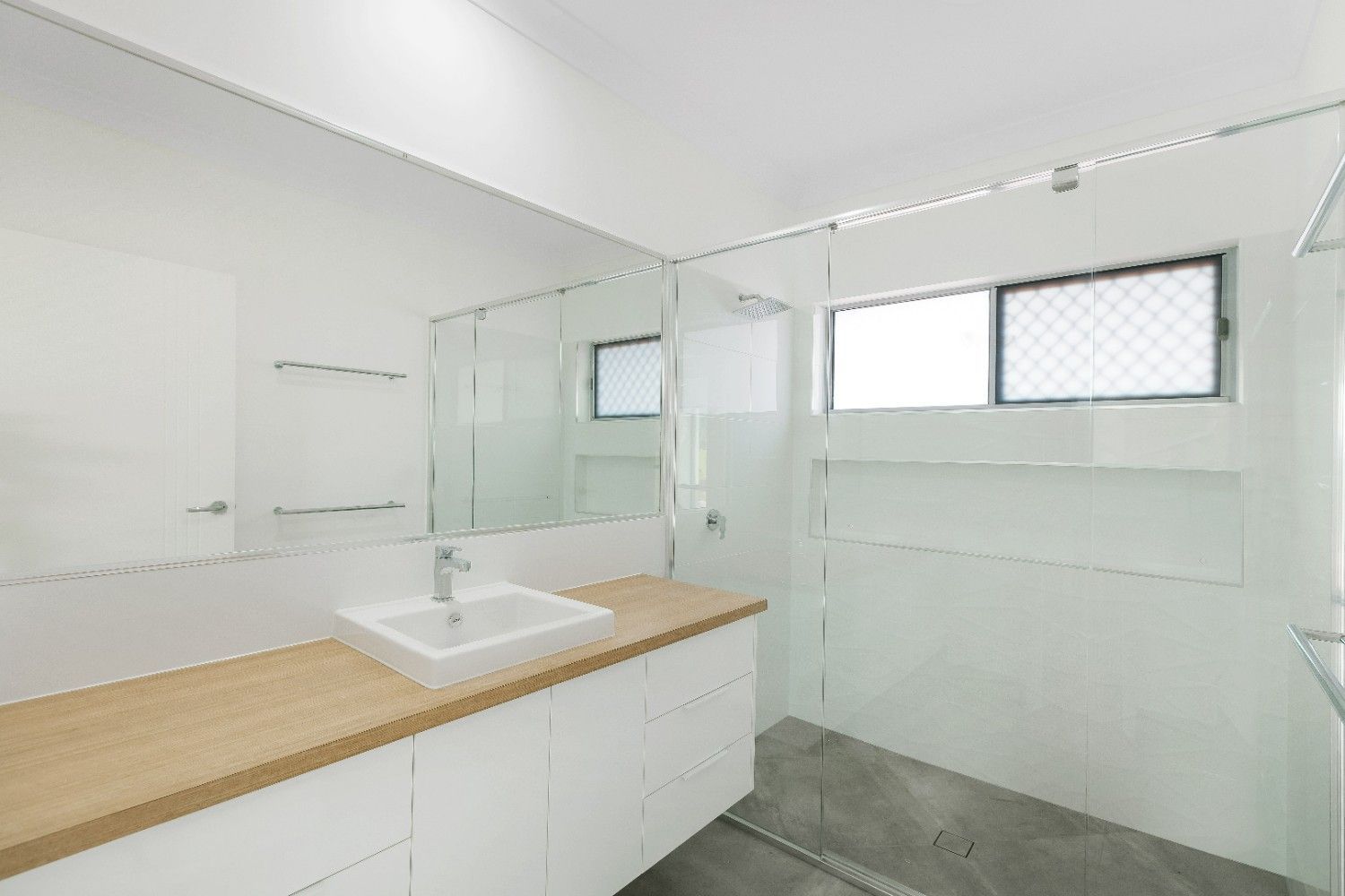 A Bathroom With a Sink, Mirror and Walk in Shower — Ashlee Jones Homes in Gordonvale, QLD