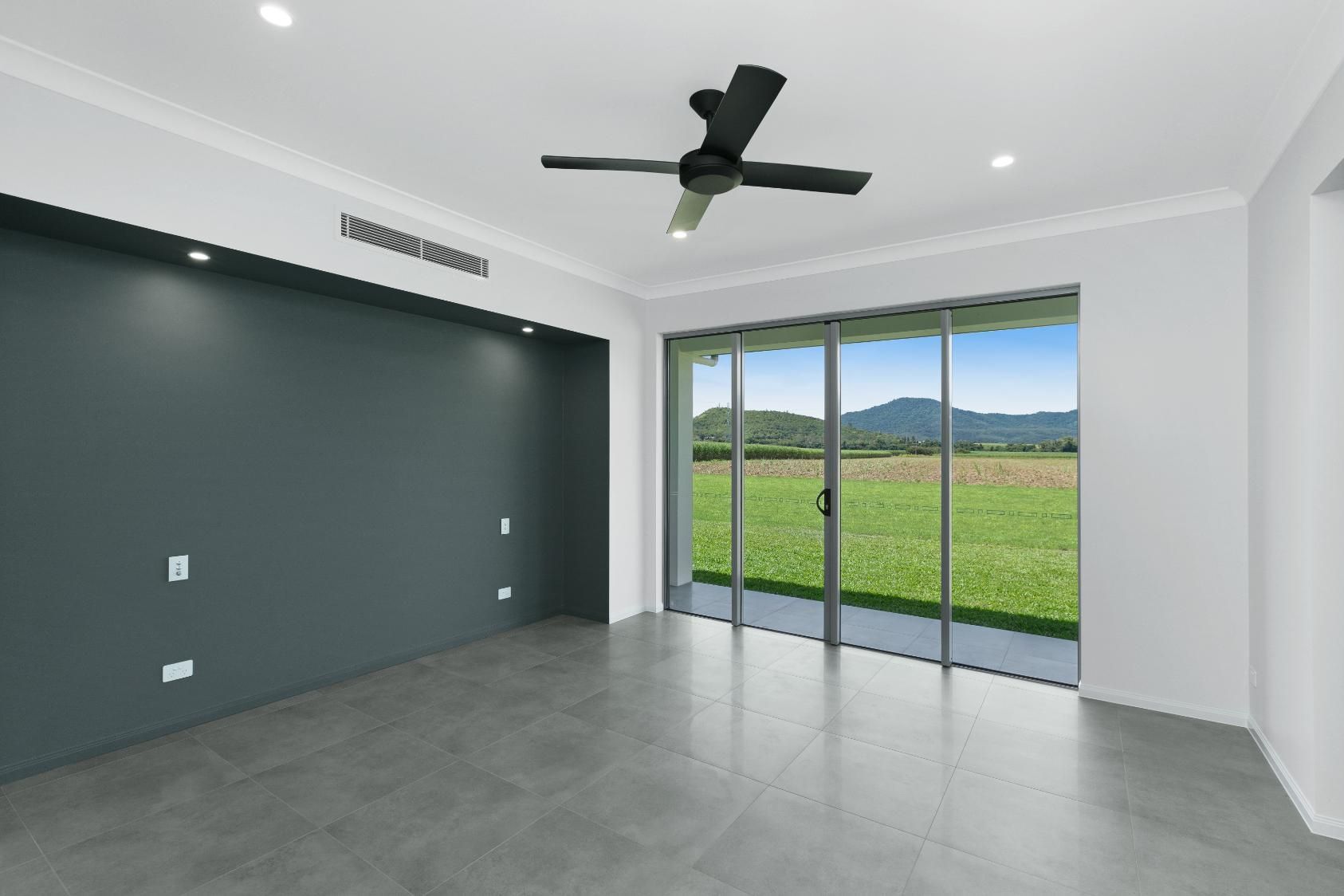 An Empty Living Room With a Ceiling Fan and Sliding Glass Doors — Ashlee Jones Homes in Gordonvale, QLD