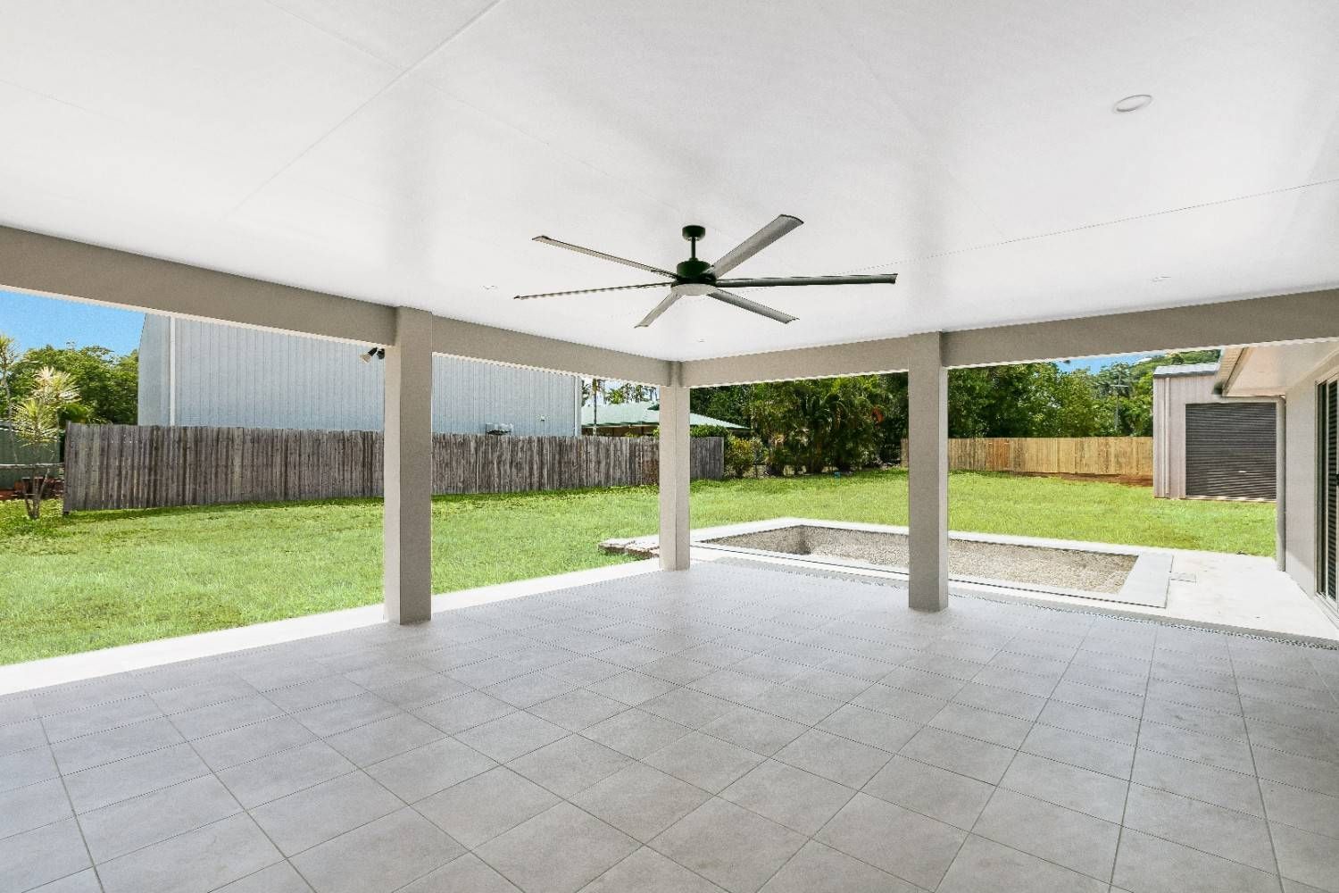 An Empty Patio With a Ceiling Fan and a Pool in the Backyard — Ashlee Jones Homes in Gordonvale, QLD