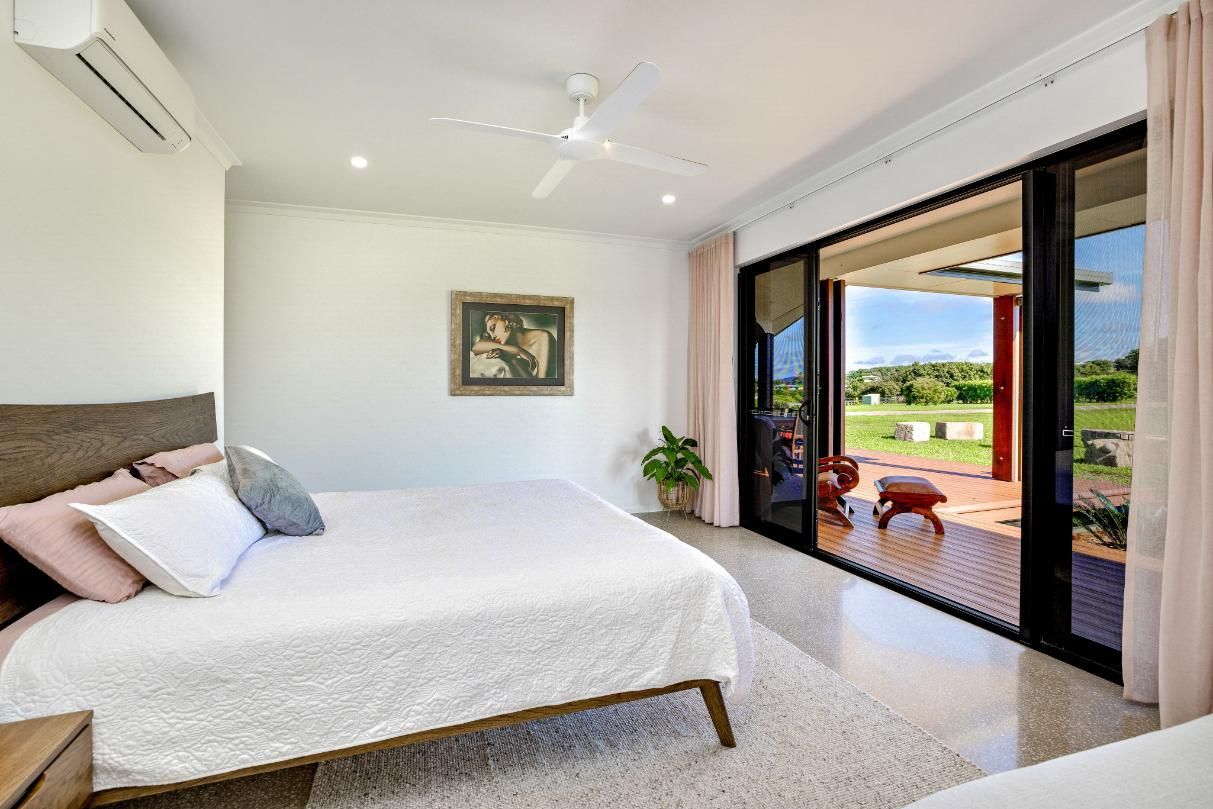 A Bedroom With a Large Bed, Sliding Glass Doors and a Ceiling Fan — Ashlee Jones Homes in Gordonvale, QLD