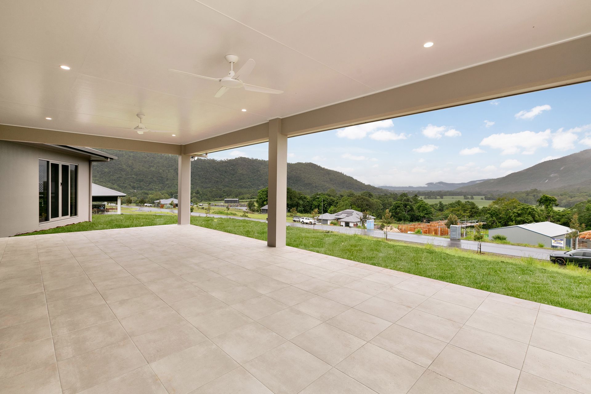 A Spacious, Covered Outdoor Patio With Light-colored Tile Flooring — Ashlee Jones Homes in Gordonvale, QLD