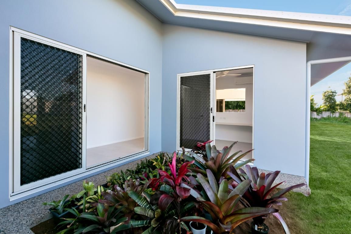 A House With a Sliding Glass Door and a Garden in Front of It — Ashlee Jones Homes in Gordonvale, QLD