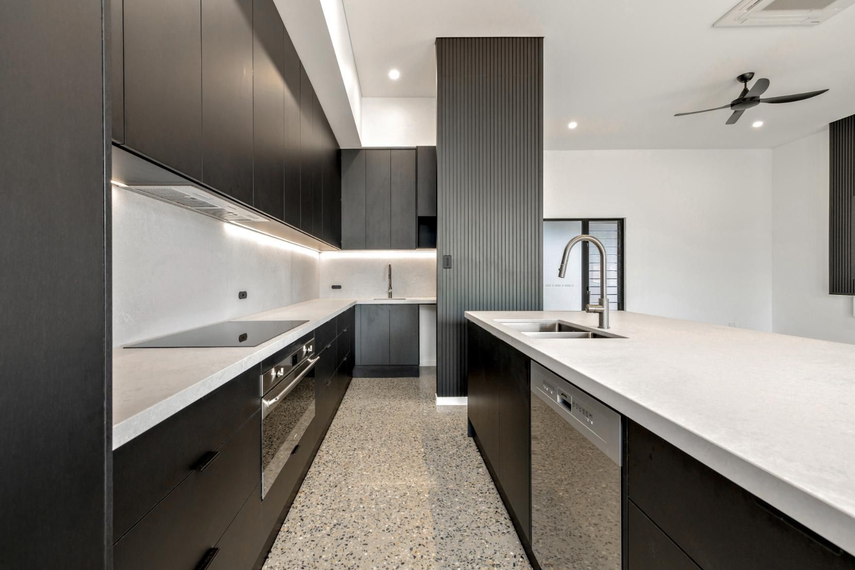 A Kitchen with Black Cabinets, White Counter Tops, Appliances and A Ceiling Fan — Ashlee Jones Homes in Gordonvale, QLD