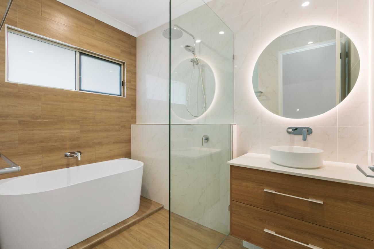 A Bathroom With a Bathtub, Sink, Mirror and Walk in Shower— Ashlee Jones Homes in Gordonvale, QLD