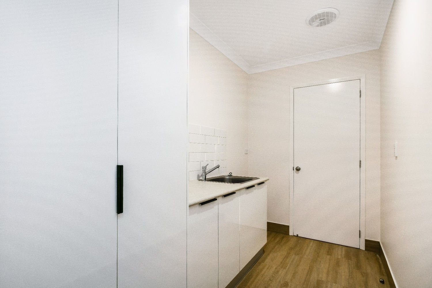 A Kitchen With White Cabinets, a Sink and a Door — Ashlee Jones Homes in Gordonvale, QLD