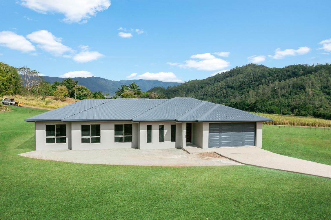 A House With a Gray Roof is Sitting on Top of a Lush Green Field — Ashlee Jones Homes in Gordonvale, QLD