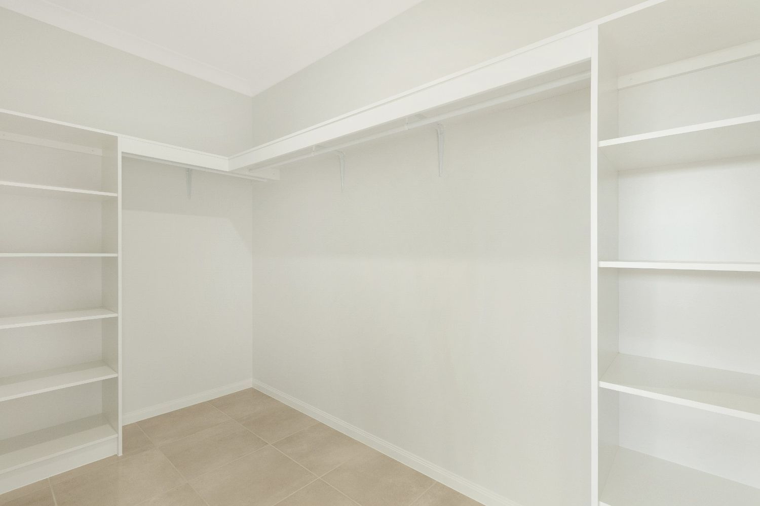 An Empty Walk in Closet With White Shelves and a Carpet — Ashlee Jones Homes in Gordonvale, QLD