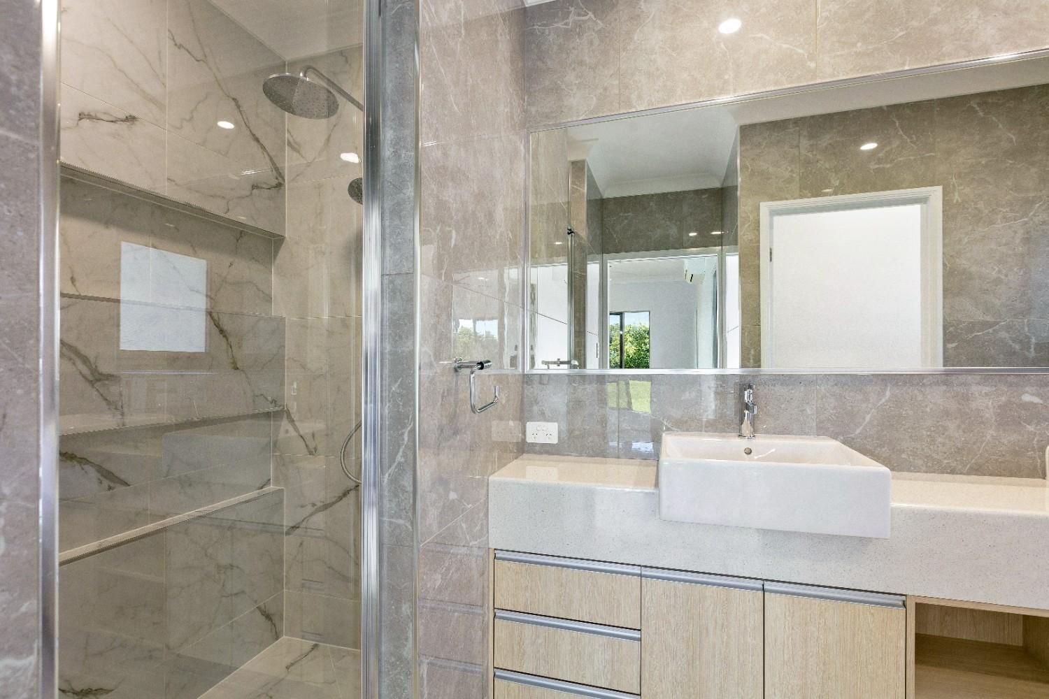 A Bathroom With a Sink, Mirror and Walk in Shower — Ashlee Jones Homes in Gordonvale, QLD