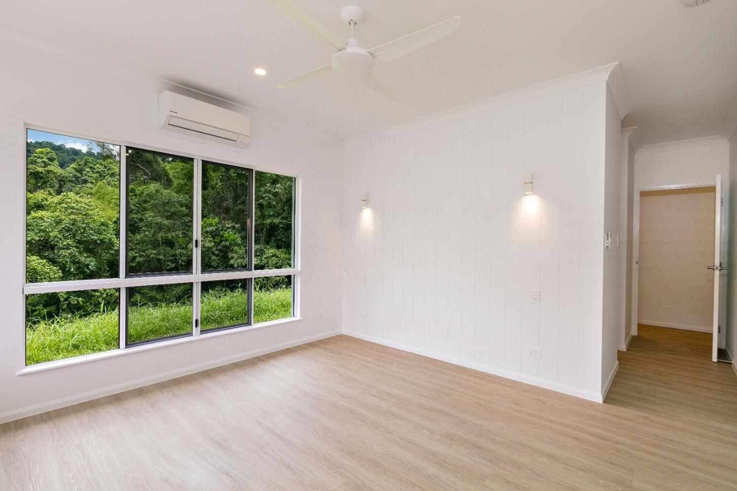 An Empty Room With a Ceiling Fan and a Large Window — Ashlee Jones Homes in Gordonvale, QLD