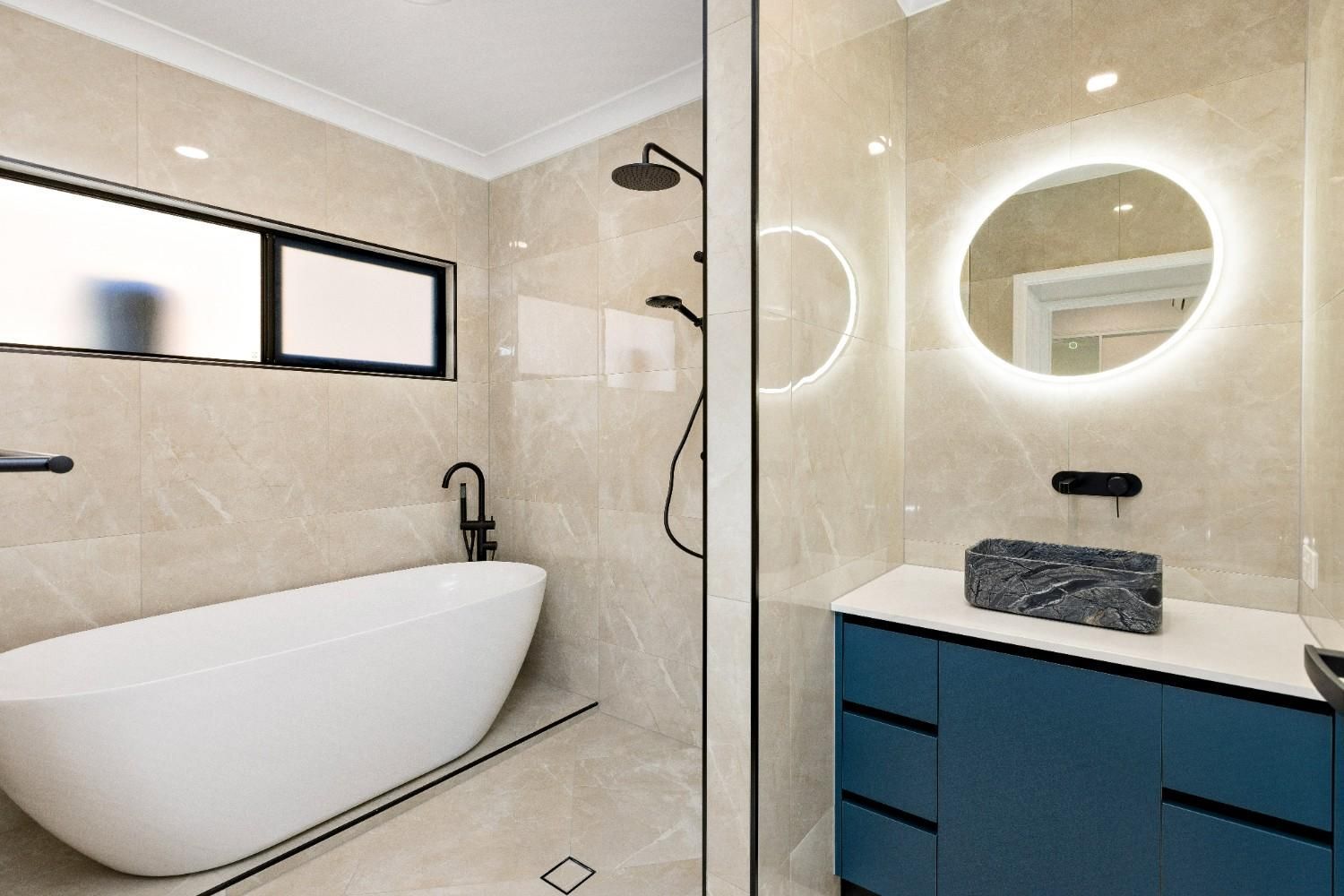 A Bathroom With a Bathtub, Sink, Shower and Mirror — Ashlee Jones Homes in Gordonvale, QLD