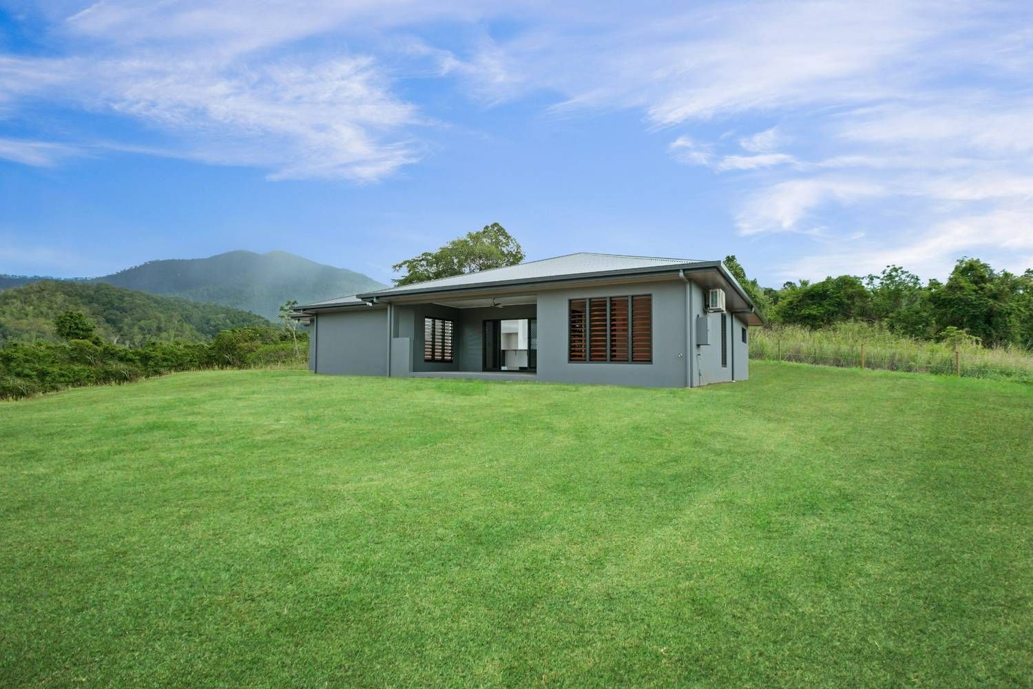 A House is Sitting in the Middle of a Lush Green Field — Ashlee Jones Homes in Gordonvale, QLD