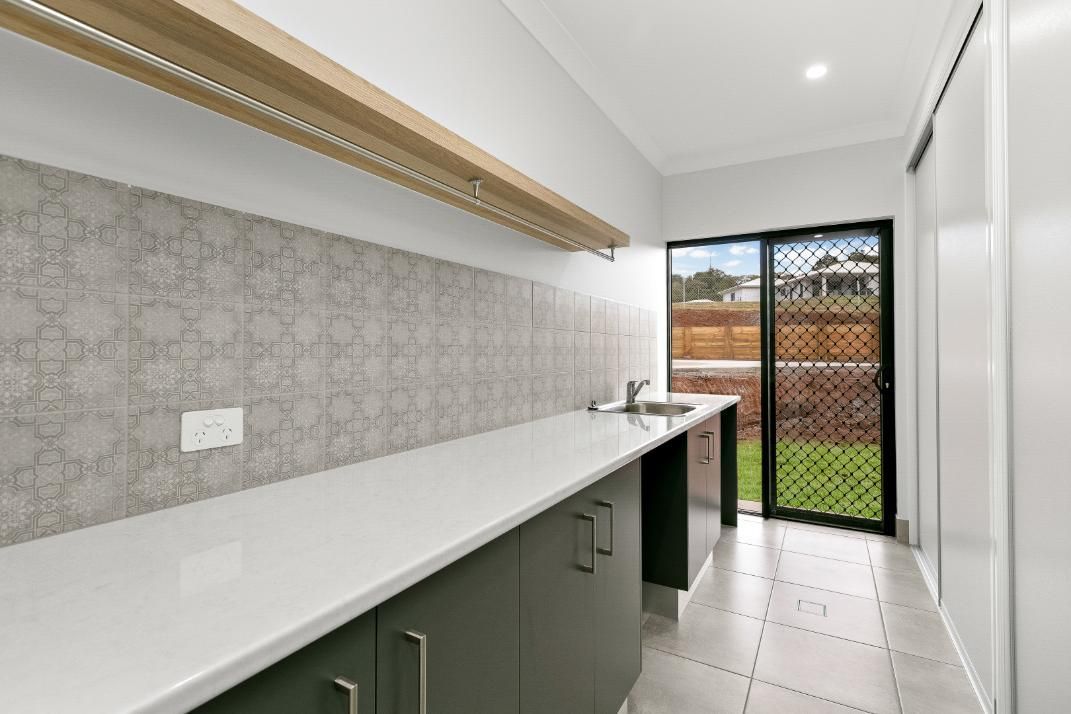 A Kitchen With a Sliding Glass Door and a Sink — Ashlee Jones Homes in Gordonvale, QLD