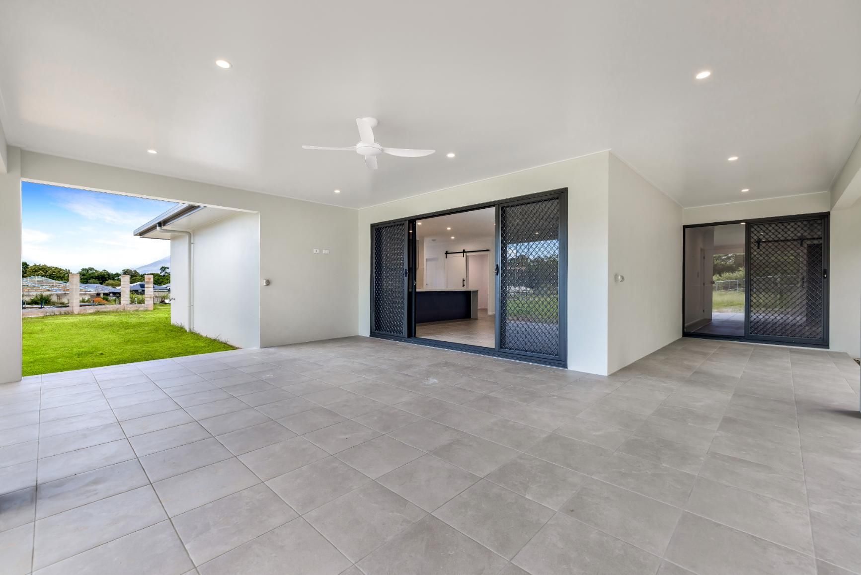 A Large Patio With Sliding Glass Doors and a Ceiling Fan in a House — Ashlee Jones Homes in Gordonvale, QLD