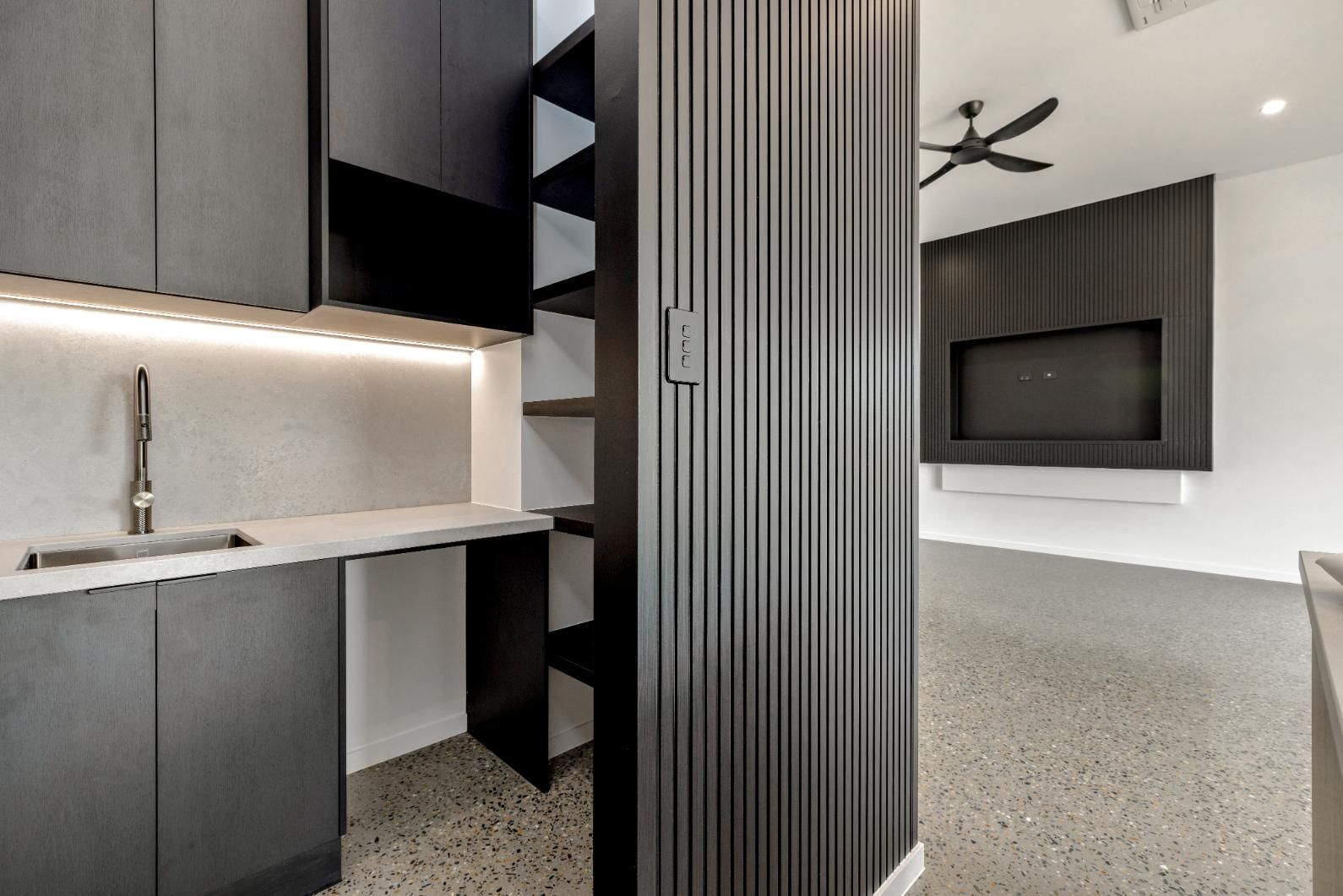 A Kitchen with Black Cabinets, a Sink, and A Ceiling Fan — Ashlee Jones Homes in Gordonvale, QLD