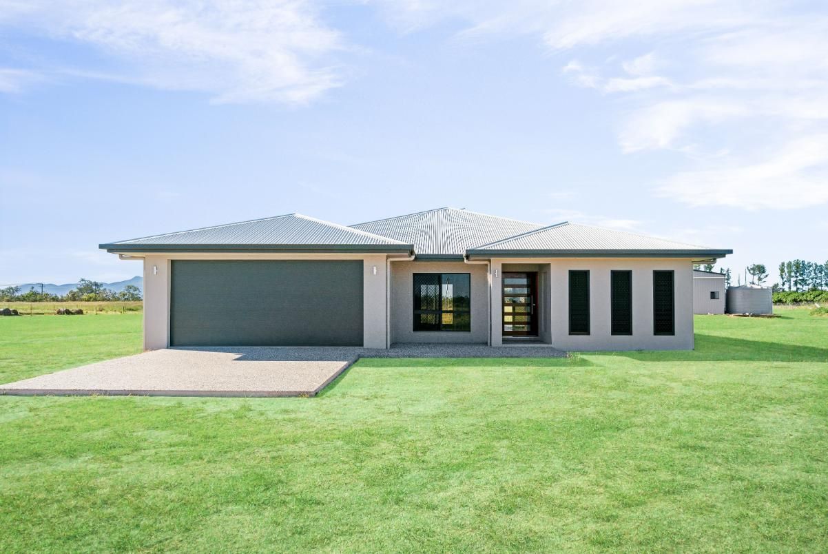 A House is Sitting on Top of a Lush Green Field — Ashlee Jones Homes in Gordonvale, QLD