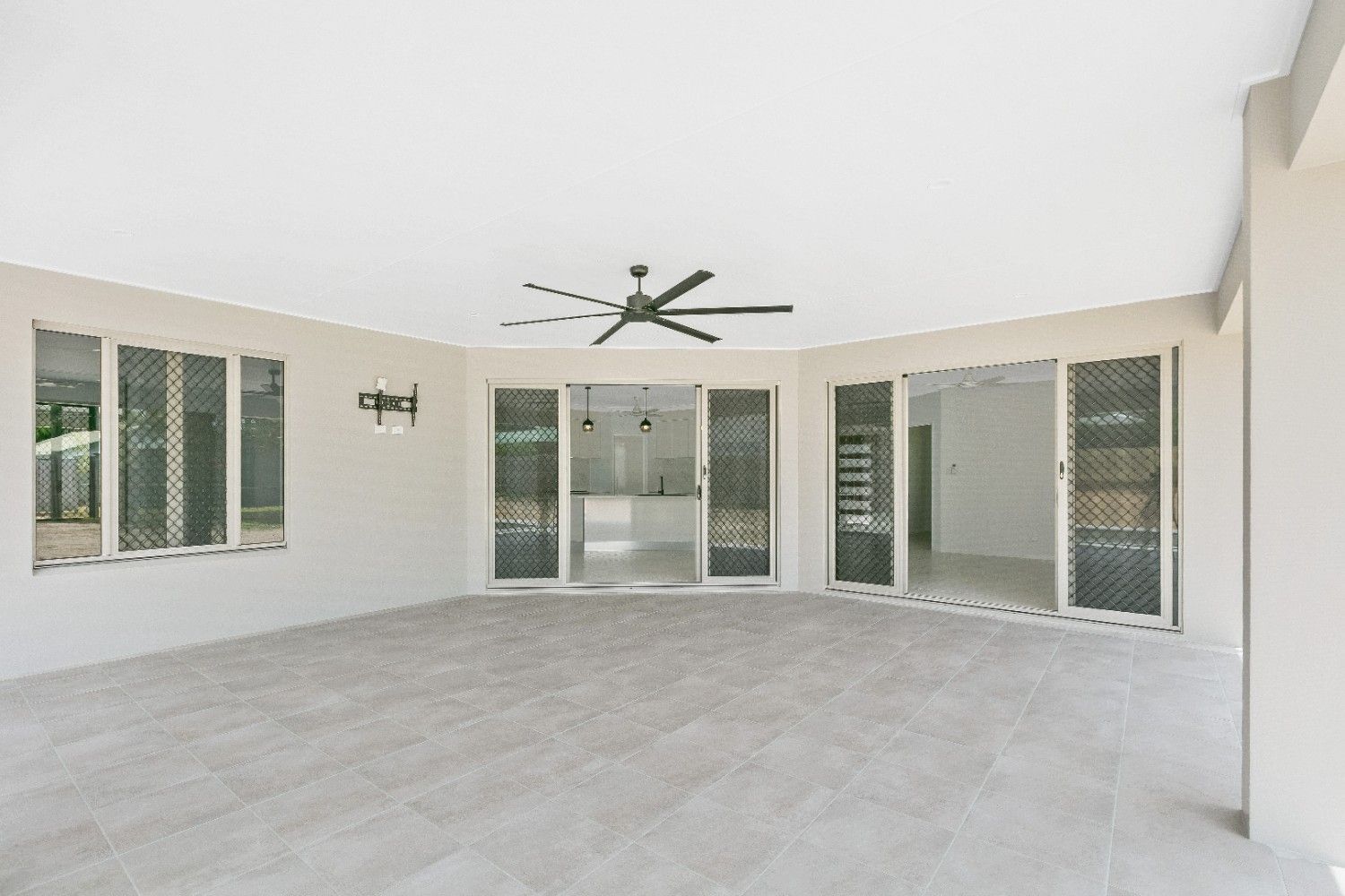 An Empty Room With a Ceiling Fan and Sliding Glass Doors — Ashlee Jones Homes in Gordonvale, QLD