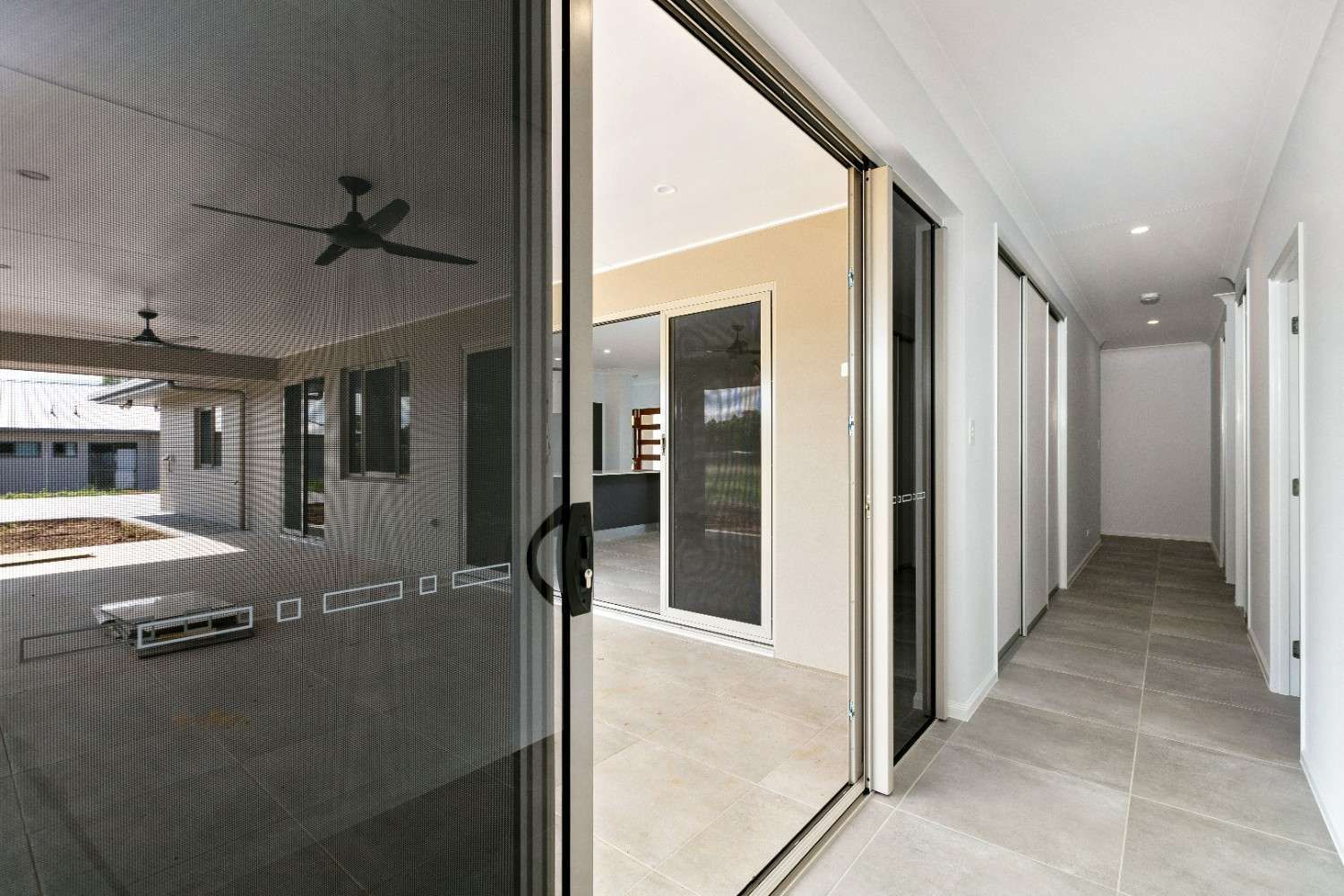 A Hallway With a Sliding Glass Door and a Ceiling Fan — Ashlee Jones Homes in Gordonvale, QLD