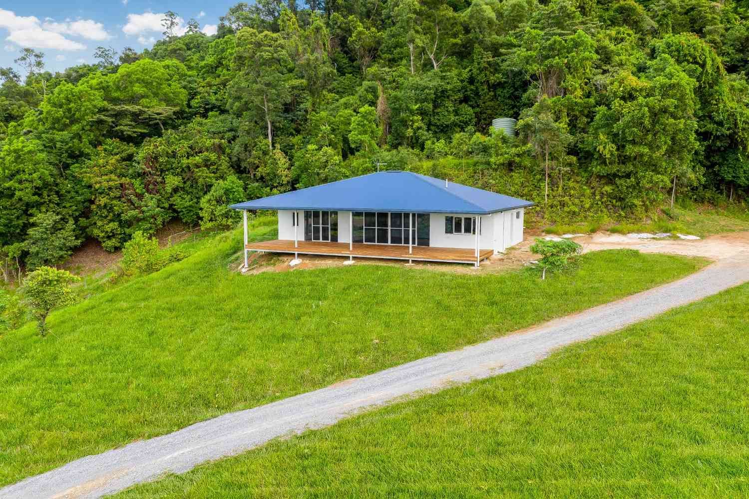 An Aerial View of a House on a Hill in the Middle of a Lush Green Field — Ashlee Jones Homes in Gordonvale, QLD