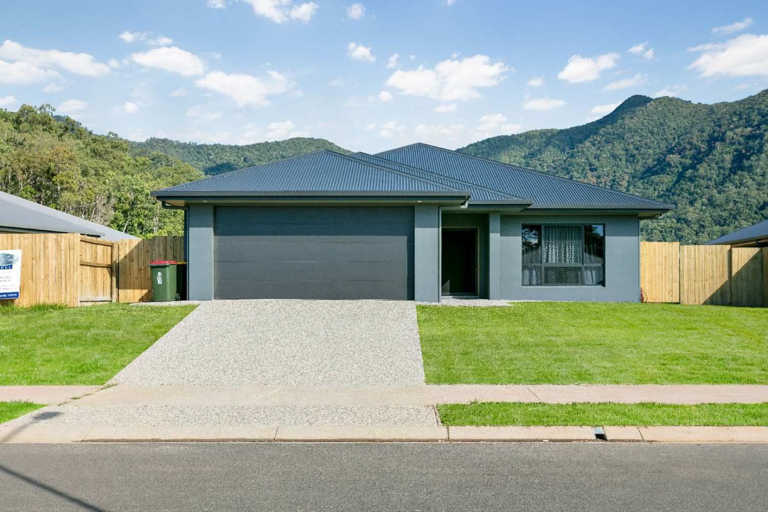 A House With a Large Garage and Mountains in the Background — Ashlee Jones Homes in Gordonvale, QLD
