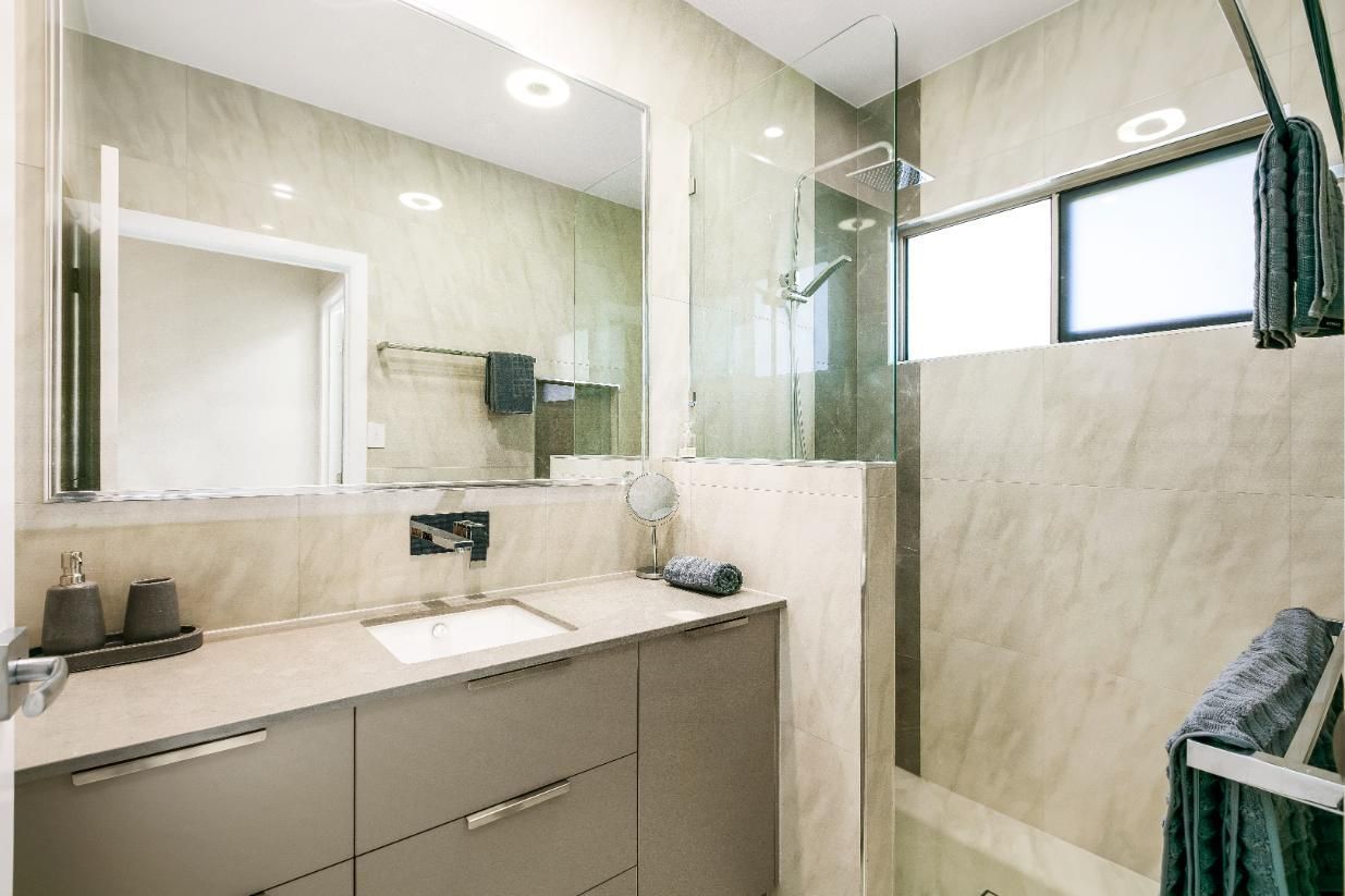 A Bathroom With a Sink, Mirror and Walk in Shower — Ashlee Jones Homes in Gordonvale, QLD