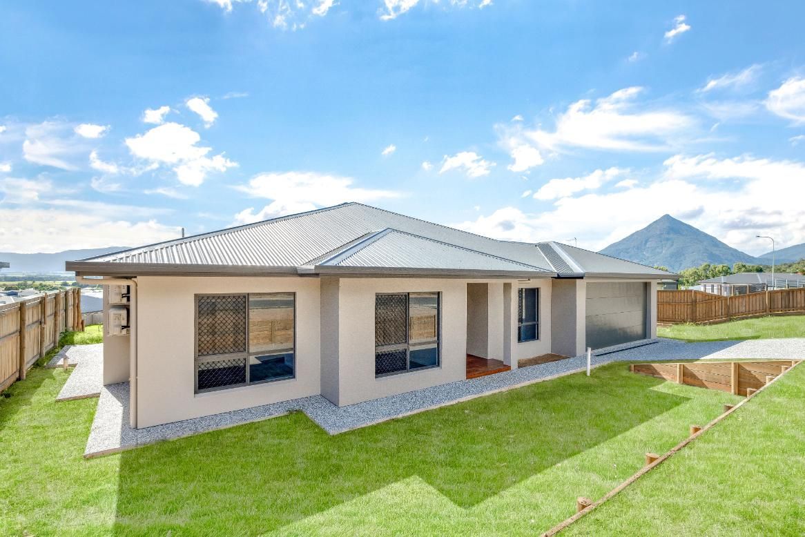 A House With a Lot of Windows is Sitting on Top of a Lush Green Lawn — Ashlee Jones Homes in Gordonvale, QLD