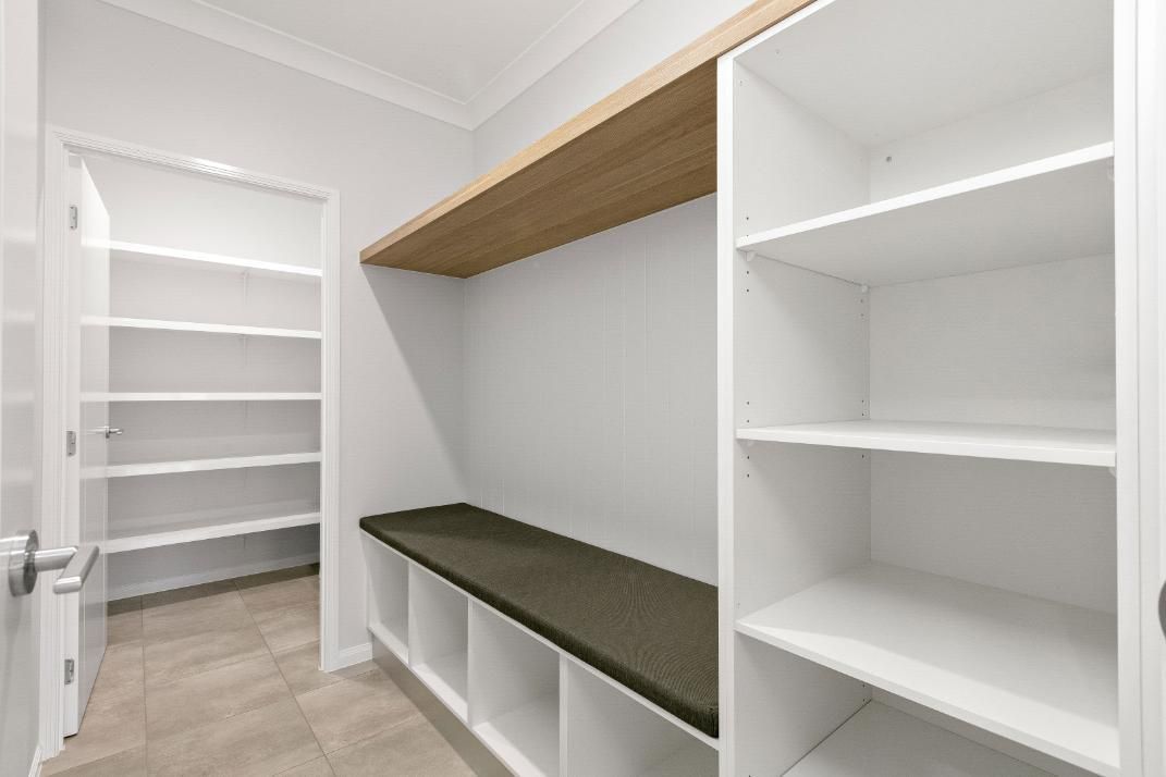 A Walk in Closet With Lots of Shelves and a Bench — Ashlee Jones Homes in Gordonvale, QLD