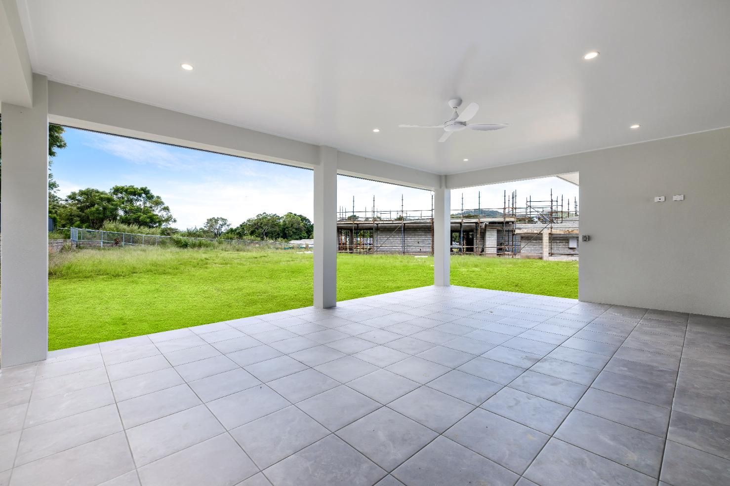 An Empty Room With a Tiled Floor and a Ceiling Fan — Ashlee Jones Homes in Gordonvale, QLD