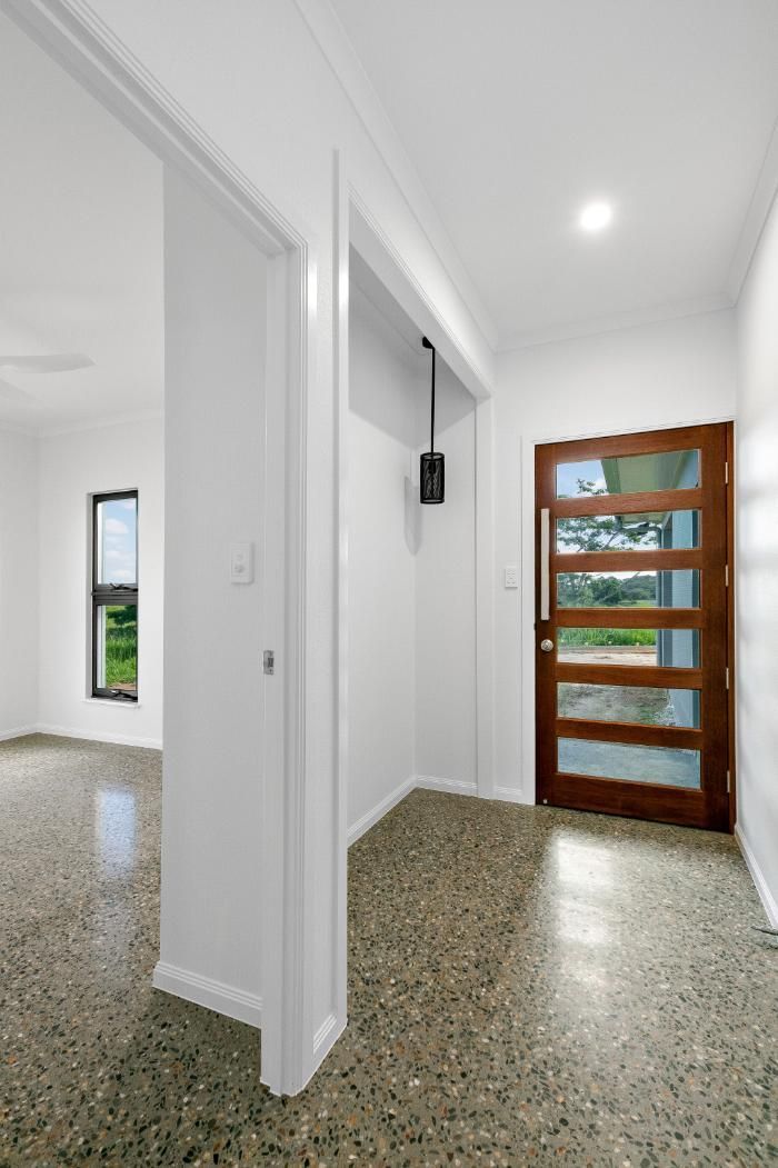 A Hallway With a Wooden Door and a White Wall — Ashlee Jones Homes in Gordonvale, QLD