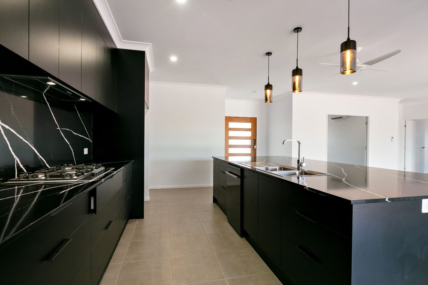 A Kitchen With Black Cabinets and Granite Counter Tops — Ashlee Jones Homes in Gordonvale, QLD