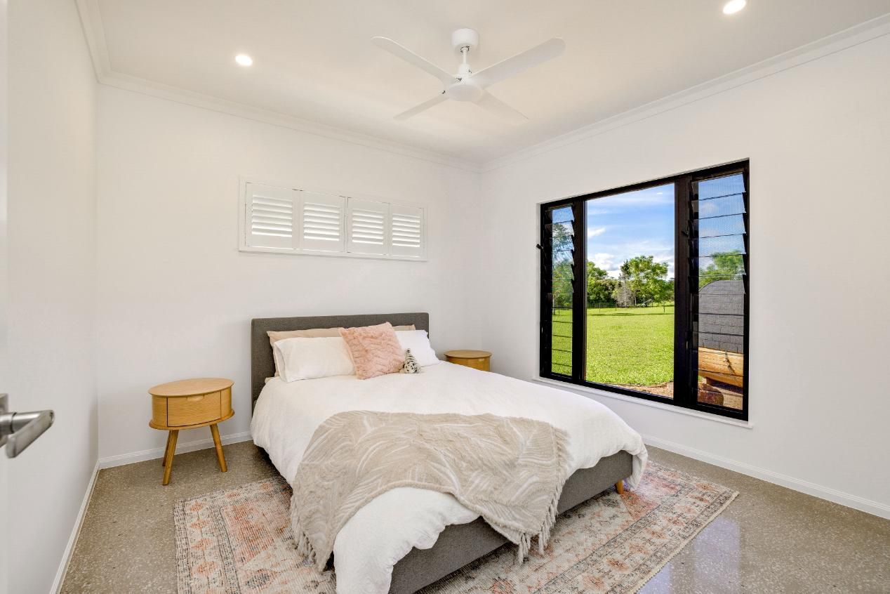 A Bedroom With a Bed and a Window With a View of a Field — Ashlee Jones Homes in Gordonvale, QLD