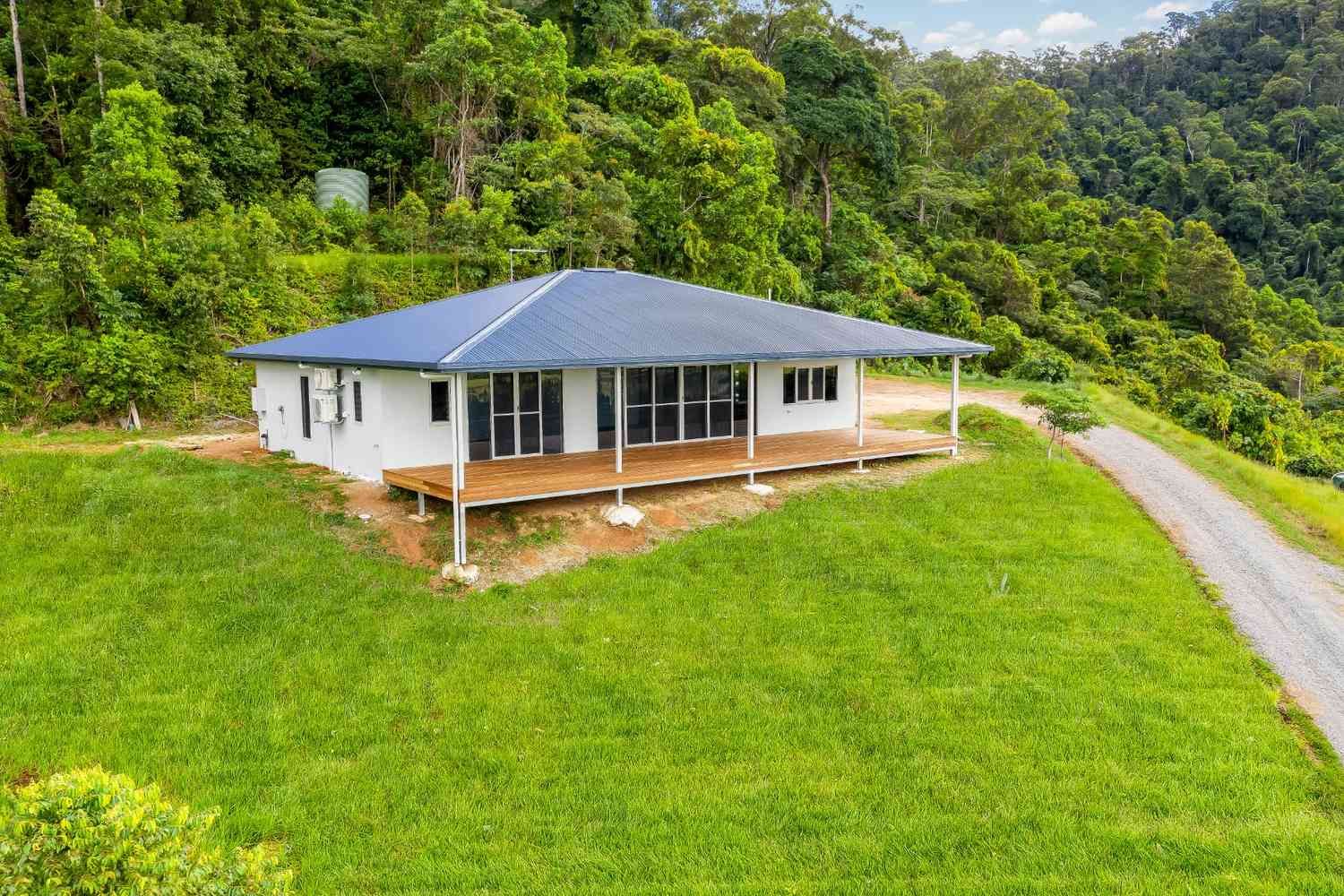 An Aerial View of a House on a Hill in the Middle of a Lush Green Forest — Ashlee Jones Homes in Gordonvale, QLD