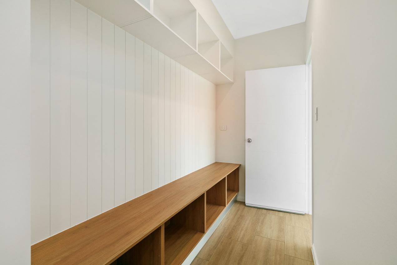A Hallway With a Wooden Bench and Shelves and a Door — Ashlee Jones Homes in Gordonvale, QLD